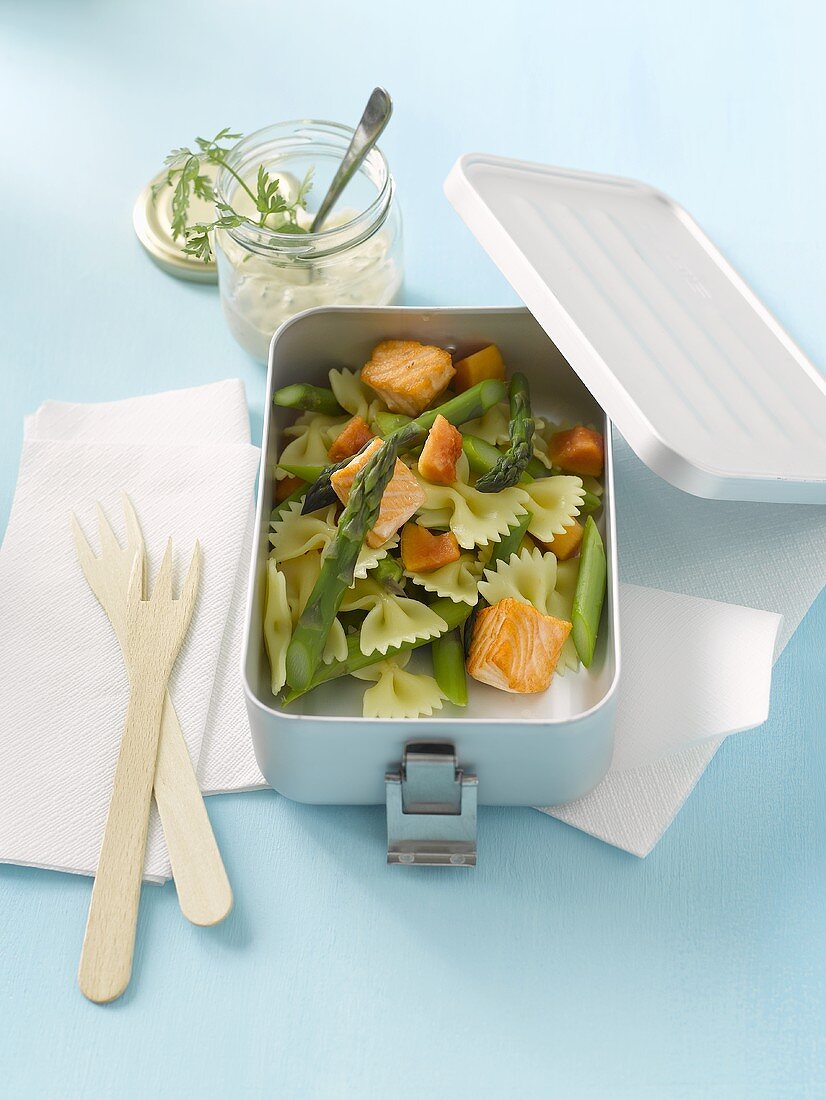 Pasta salad with salmon and green asparagus in lunch box