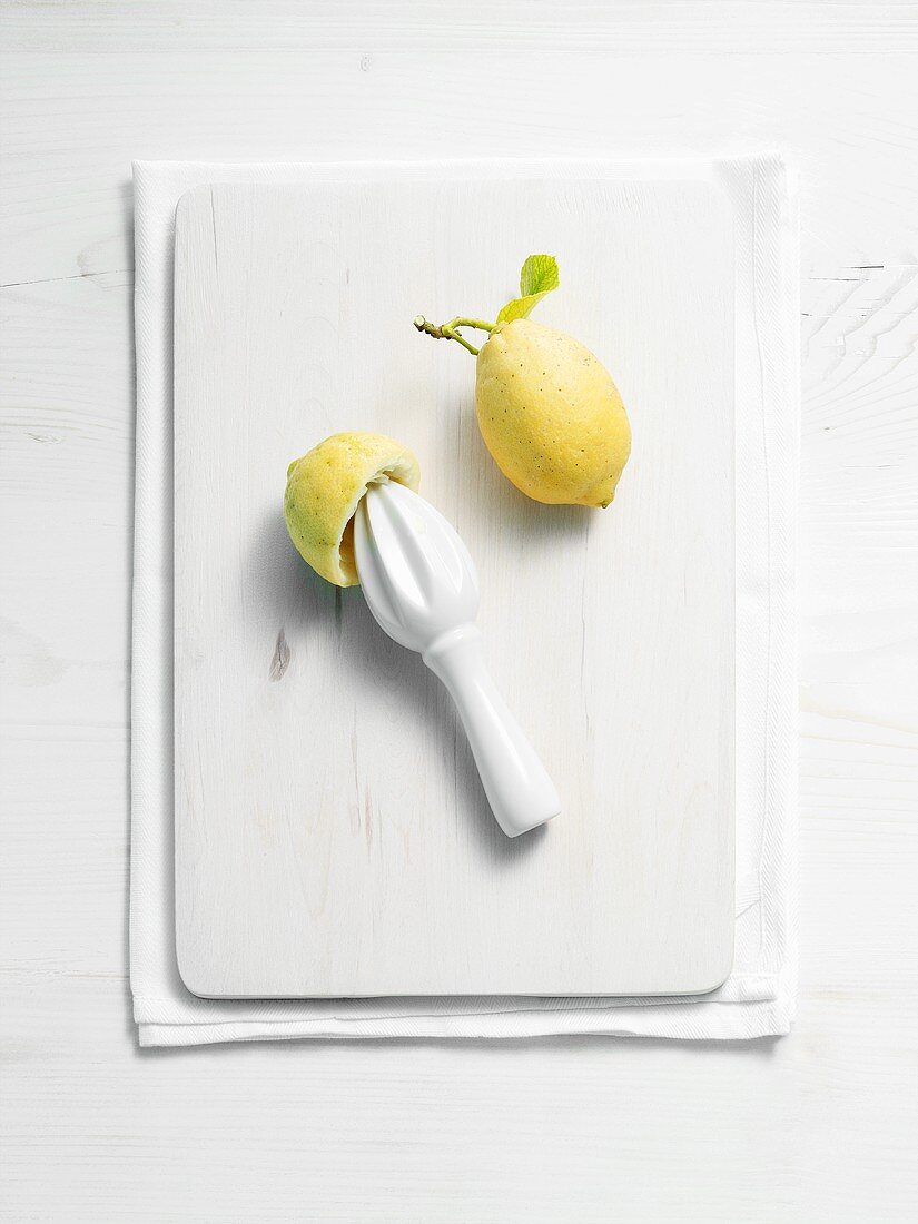 Whole lemon and squeezed lemon half with lemon squeezer