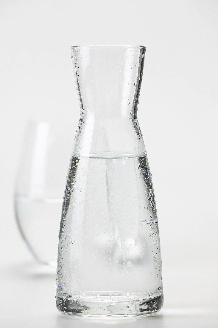 Eine Karaffe mit Mineralwasser und Glas im Hintergrund