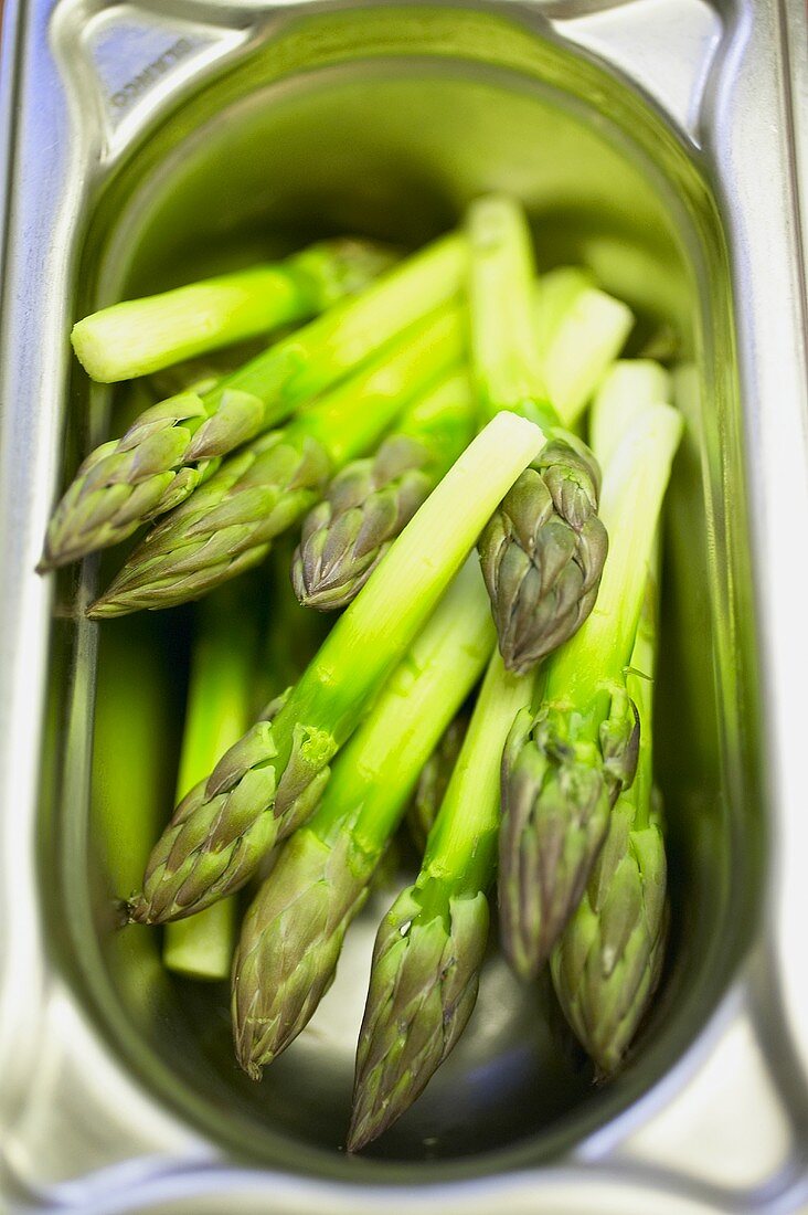 Green asparagus tips in a Gastronorm container