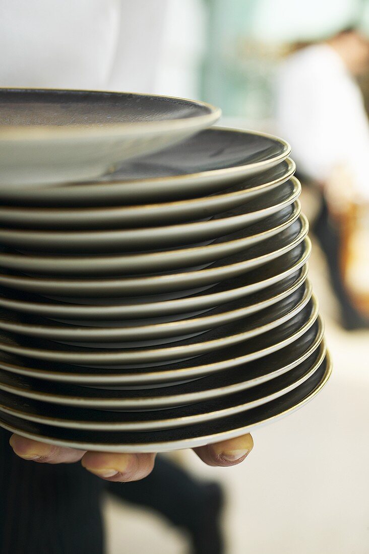 Waiter holding a pile of plates in his hands