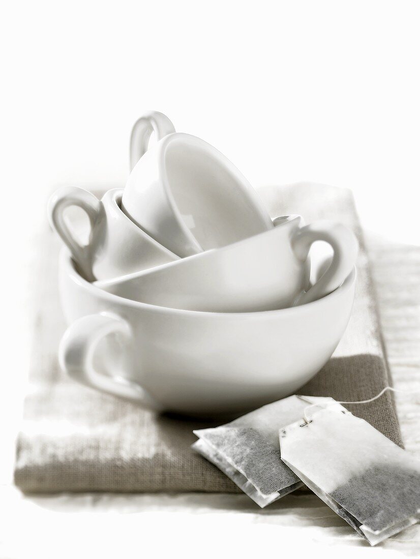 Four stacked cups with tea bags in foreground