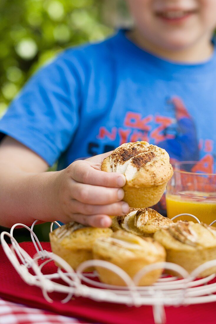 Small boy reaching for apple and cinnamon muffins