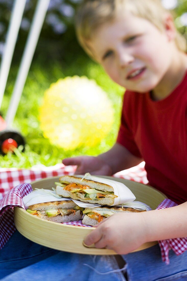 Child holding tray of focaccia sandwiches