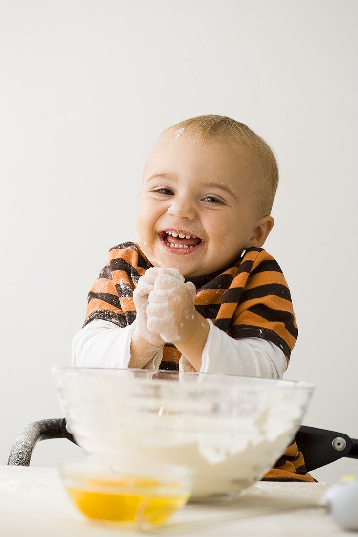 Small boy with floury hands in front of bowl of flour