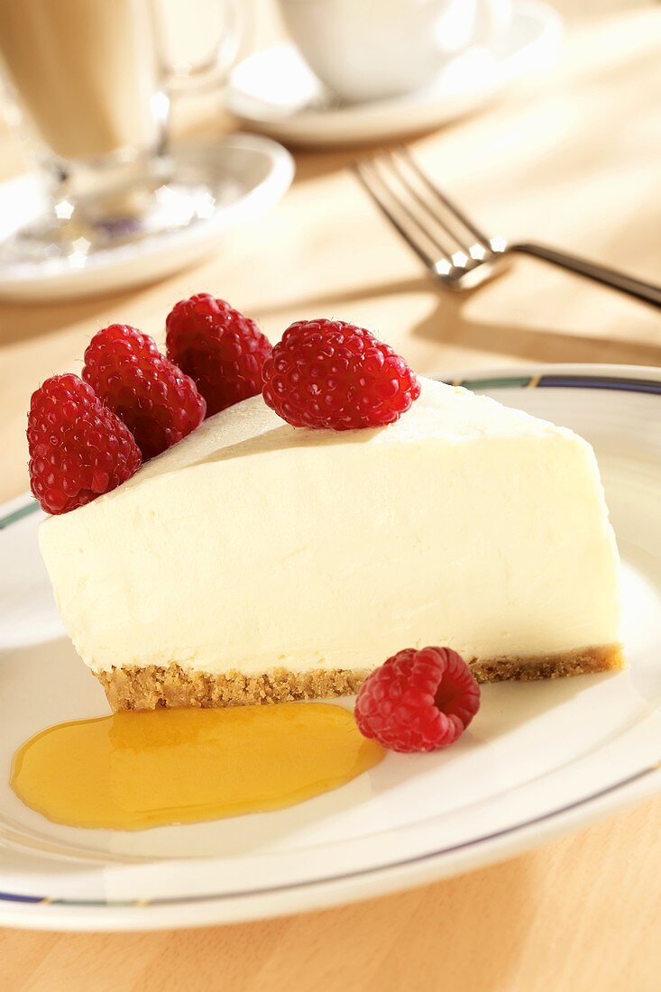 A slice of cheesecake with raspberries and fruit sauce