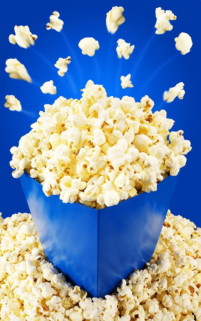 Popcorn fliegt aus blauer Tüte
