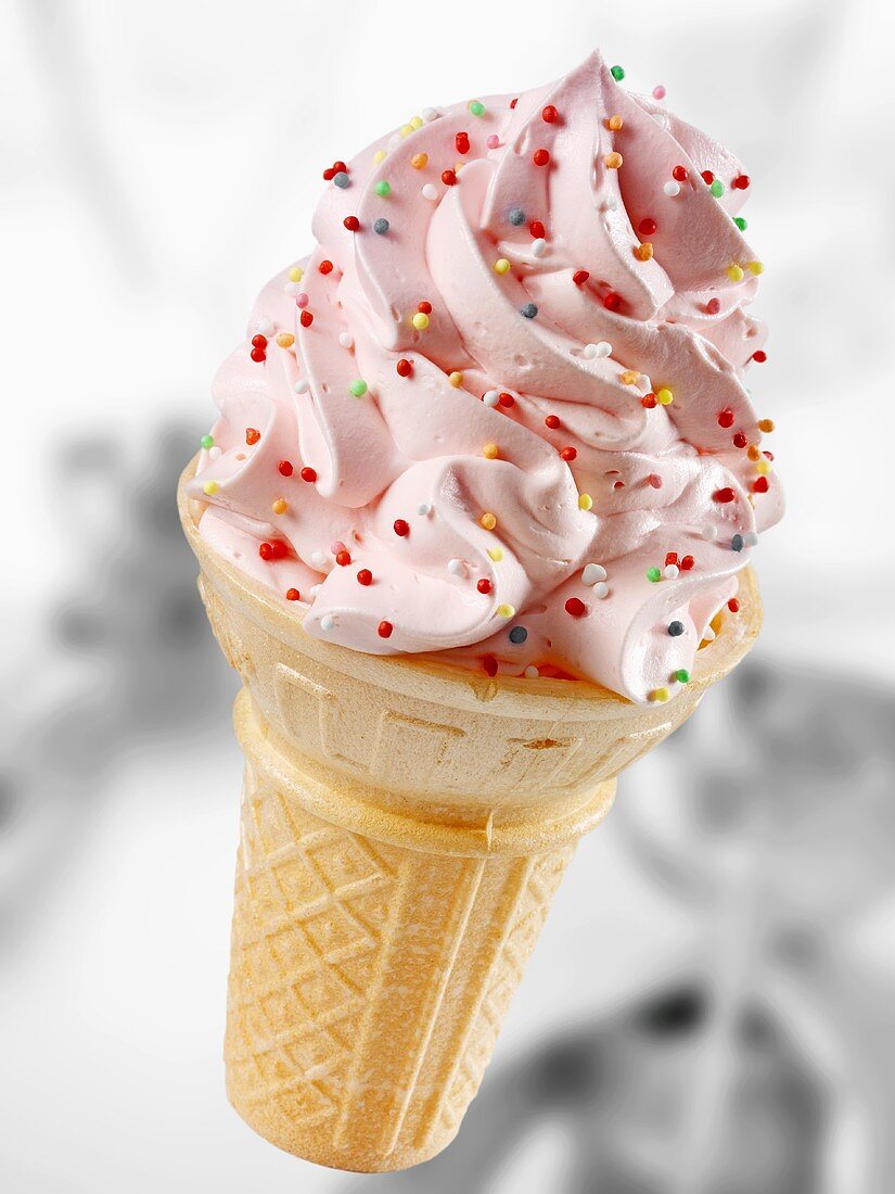 Cone of soft strawberry ice cream with coloured sprinkles