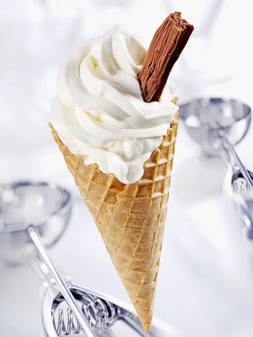 Cone of soft vanilla ice cream with chocolate flake