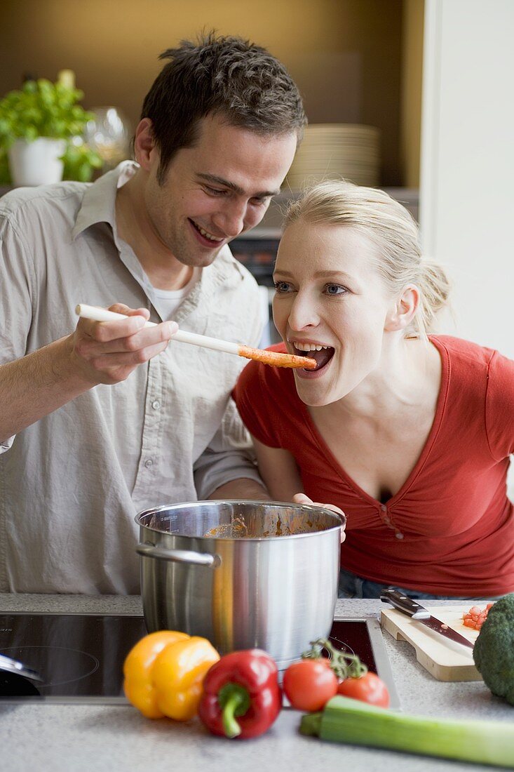 Young couple tasting tomato sauce