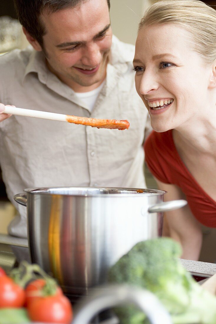 Young couple tasting tomato sauce