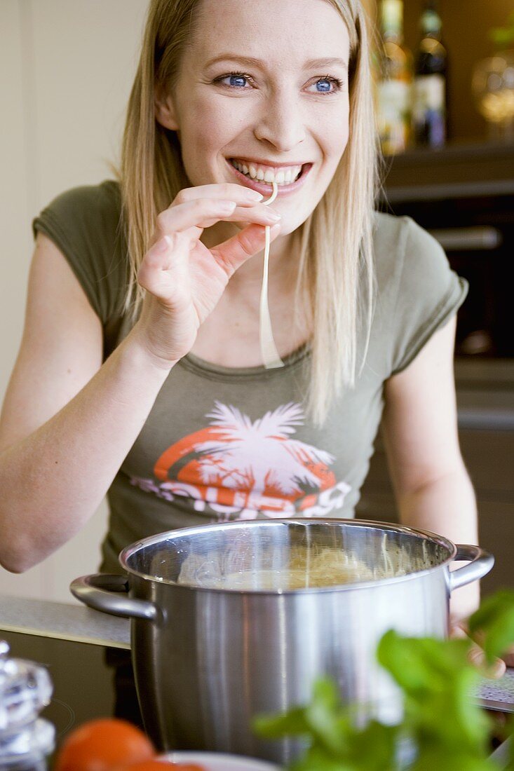 Junge Frau probiert eine gekochte Spaghetti