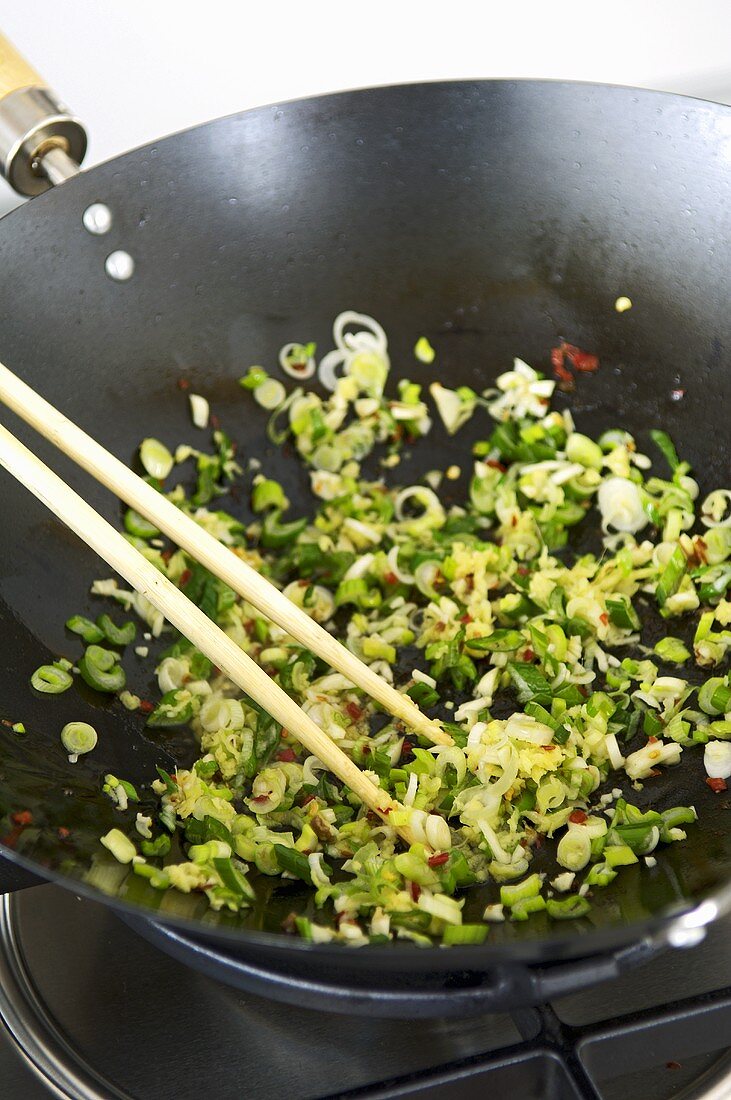 Frühlingszwiebel, Knoblauch und Chili im Wok andünsten