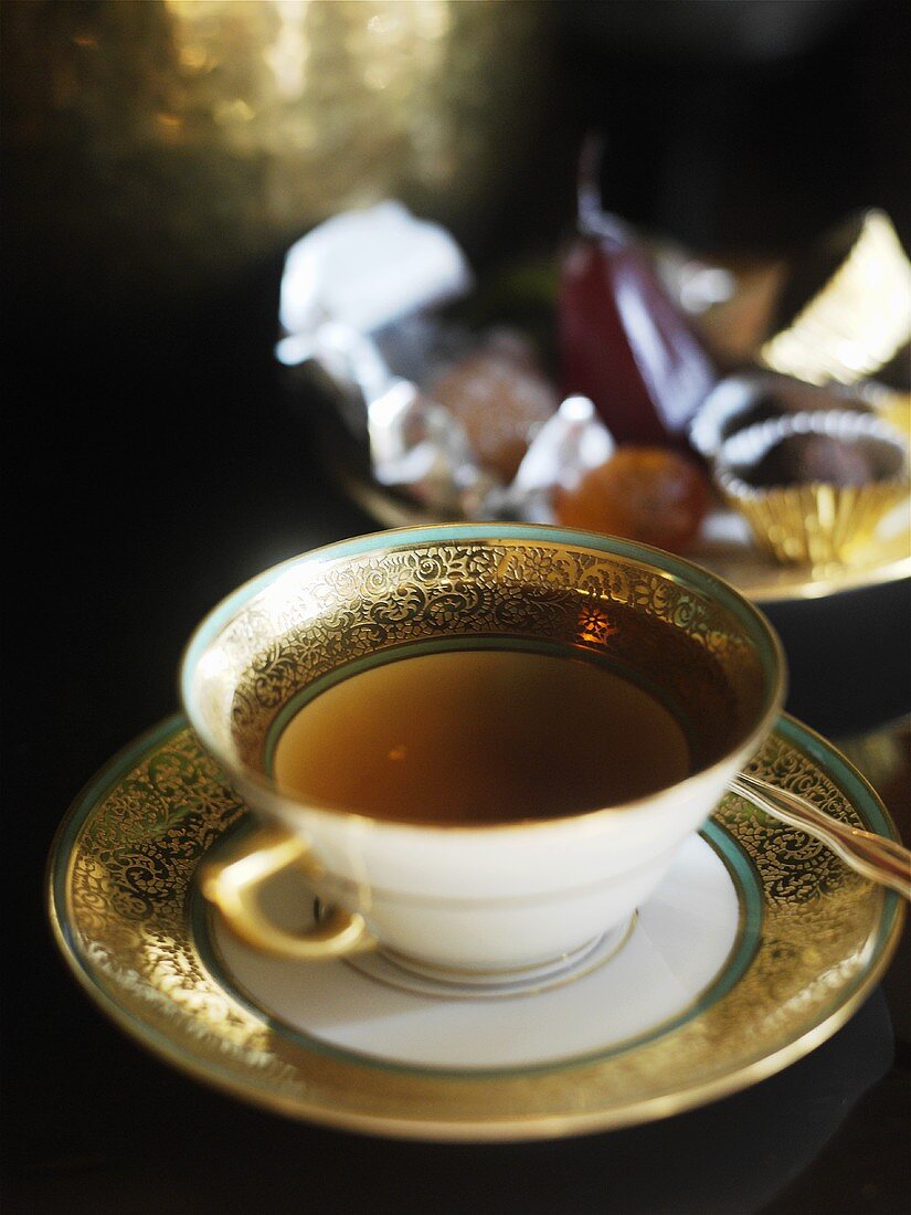 Eine Tasse Tee mit Trüffelpralinen im Hintergrund