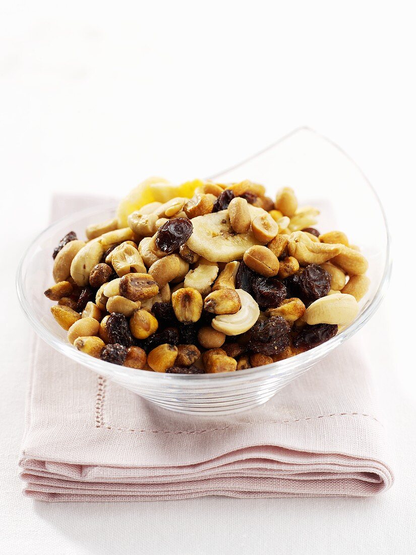 Trail mix with dried fruit, nuts, dried banana in glass bowl