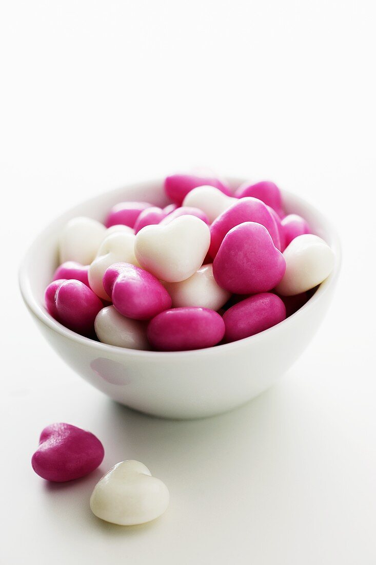 Pink and white heart-shaped mints in a small bowl