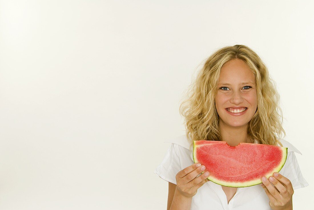 Blonde Frau hält eine Melonenspalte in den Händen