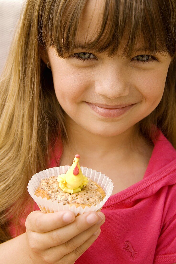 Kleines Mädchen hält einen Muffin mit Marzipan-Huhn