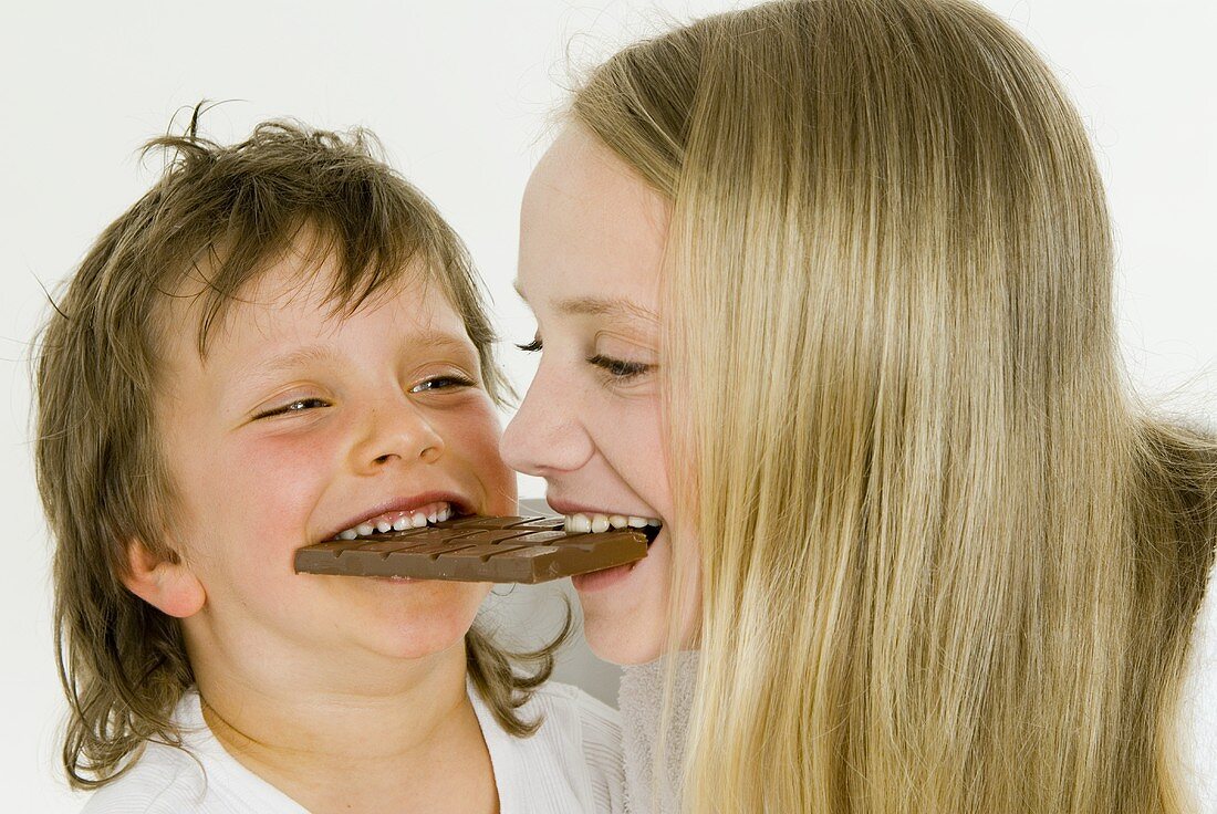 Junge und Mädchen beissen zusammen in eine Schokoladentafel