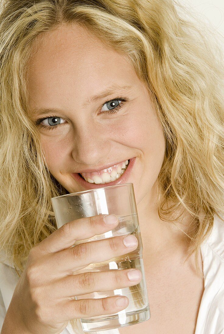 Junge Frau hält ein Glas Wasser in der Hand