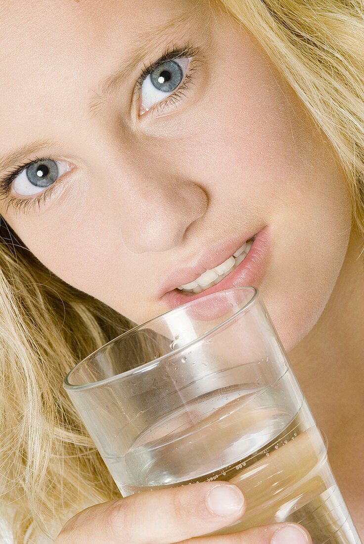 Junge Frau hält ein Glas Mineralwasser