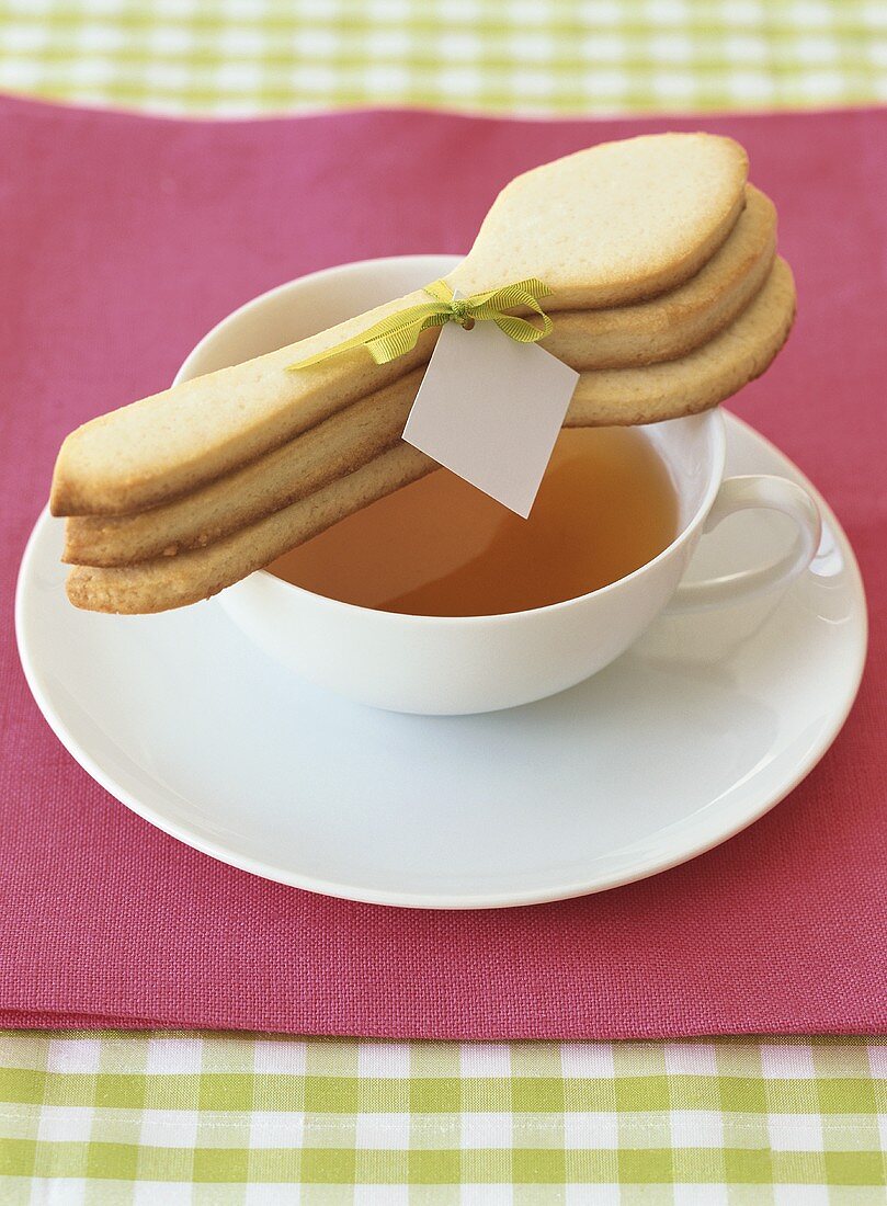 A cup of tea with three baked spoon-shaped biscuits