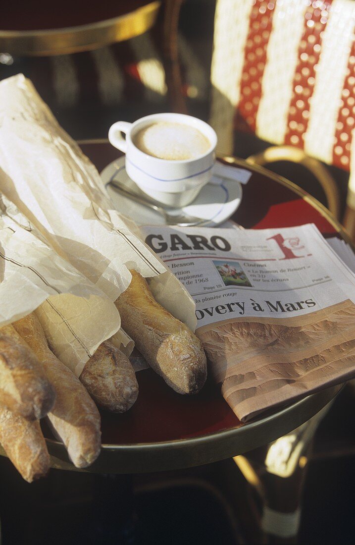 Fresh baguettes and cappuccino on a table with newspaper