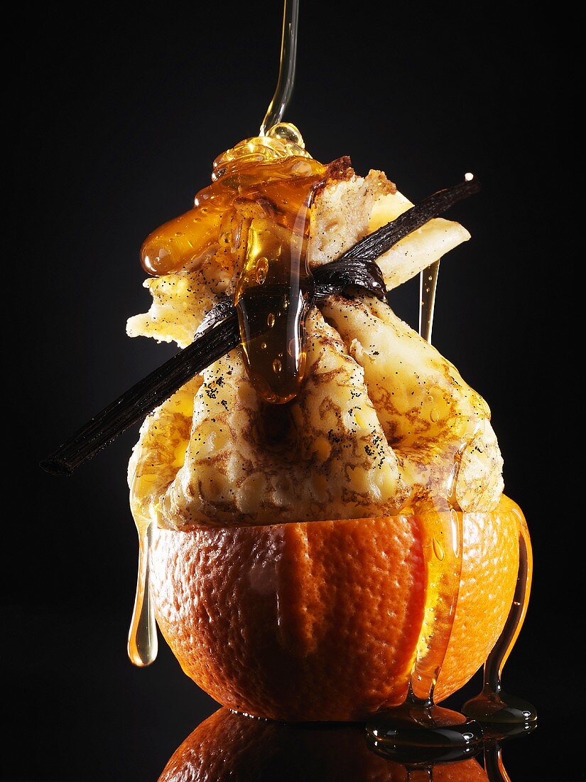 Honig fliesst über Crepe in halber Orange
