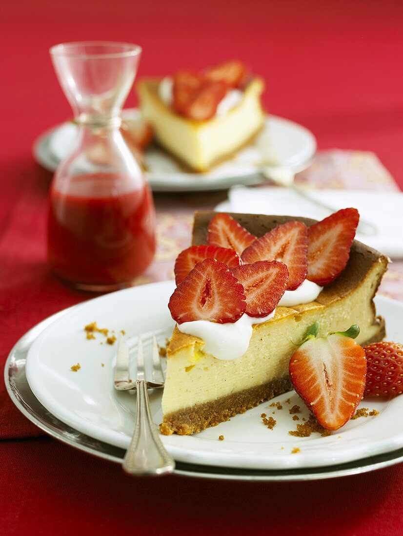 Two pieces of cheesecake with fresh strawberries