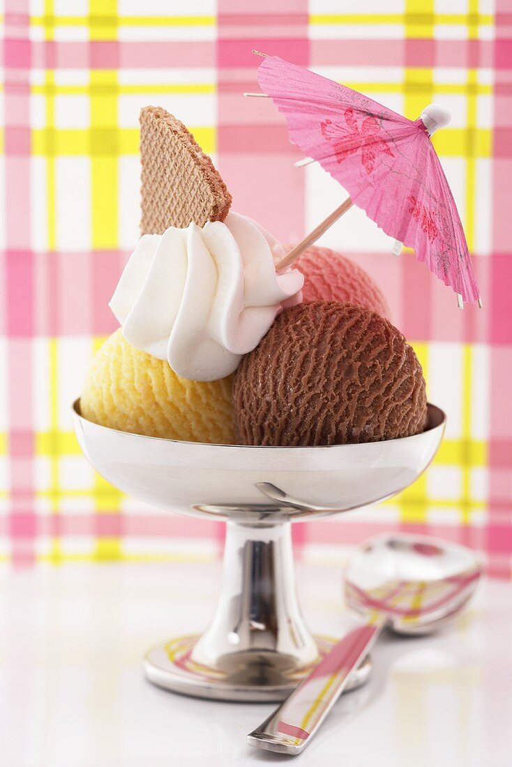 Neapolitan ice cream sundae with cream & cocktail umbrella