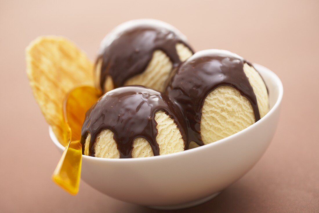 Three scoops of vanilla ice cream with chocolate sauce & wafer