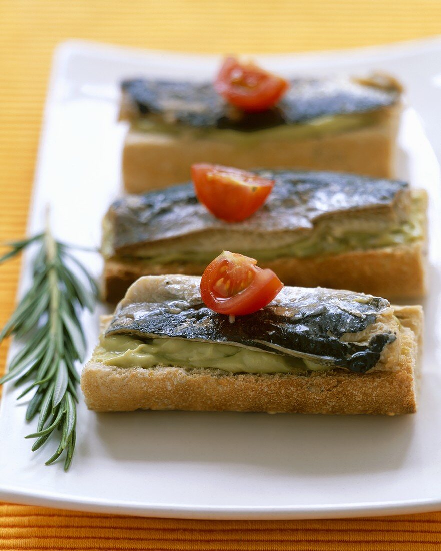 Pieces of French stick topped with guacamole and sardines