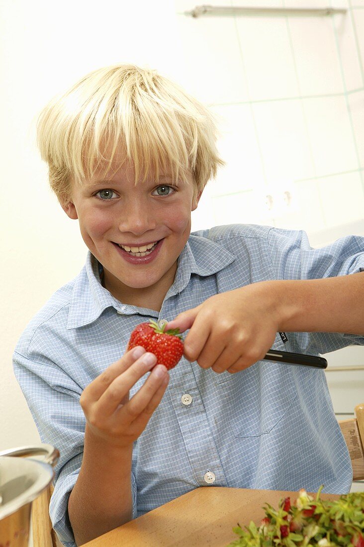 Blond boy hulling strawberries