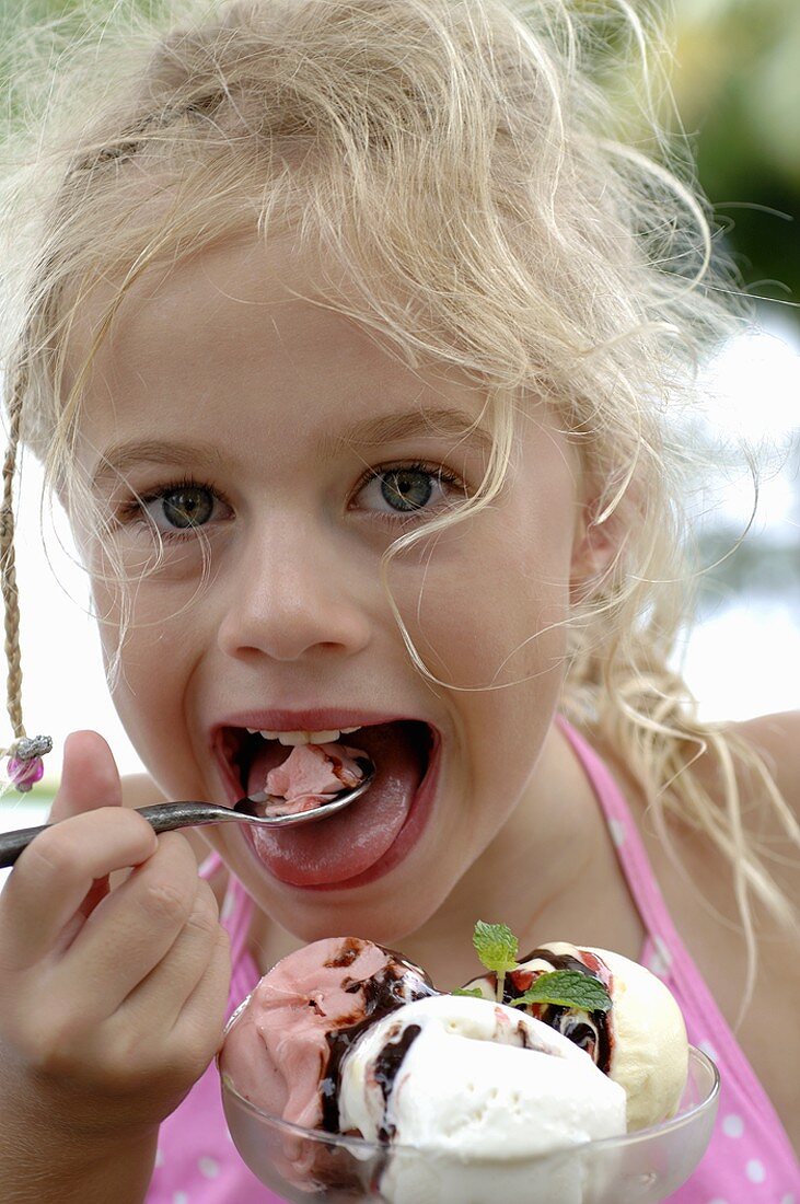 Blondes Mädchen isst einen gemischten Eisbecher
