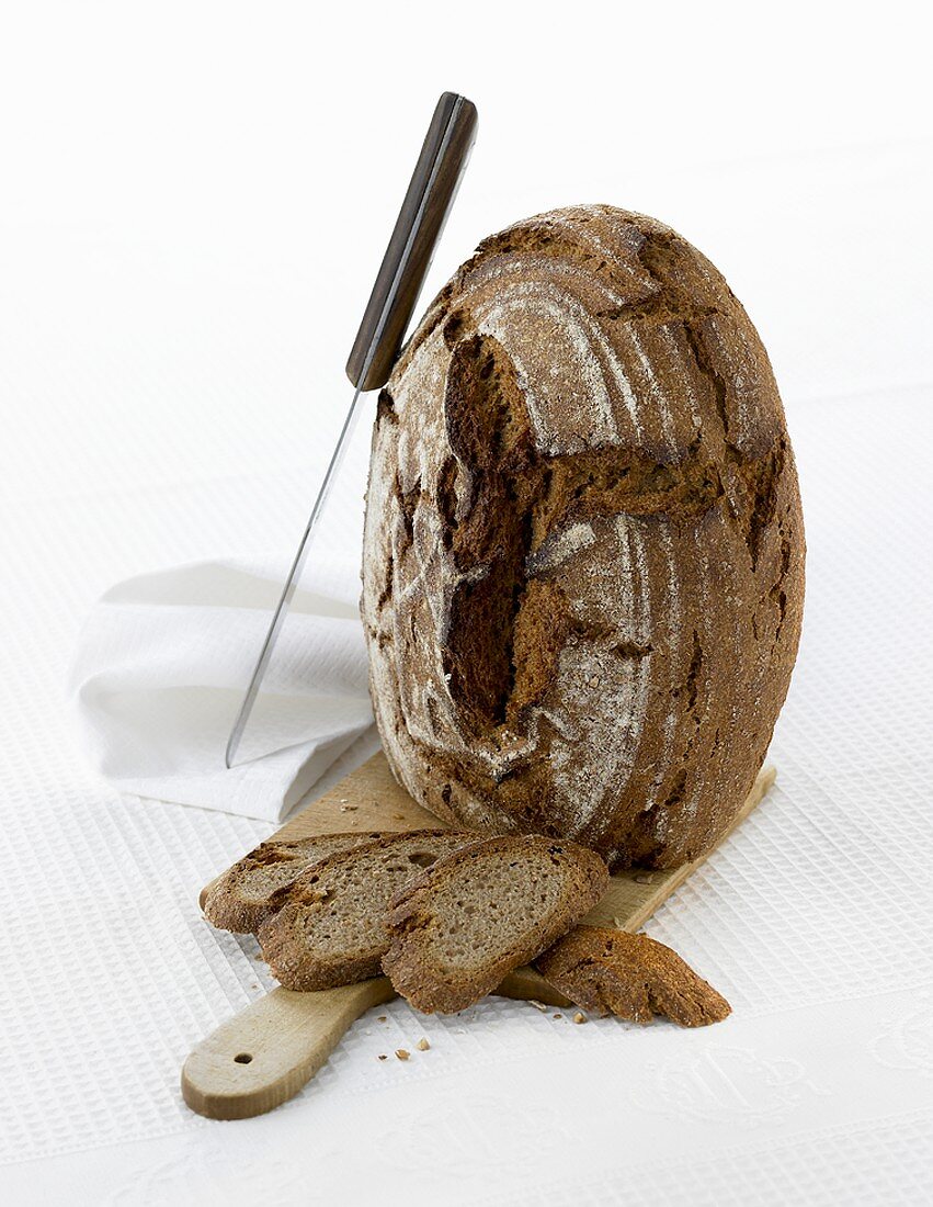 A loaf of rye bread, standing on its end, with knife