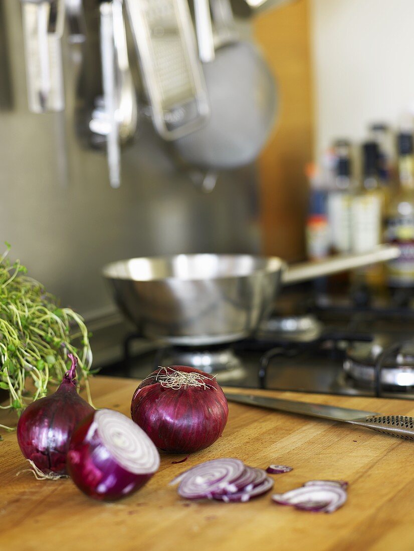 Red onions, whole and sliced on a wooden board