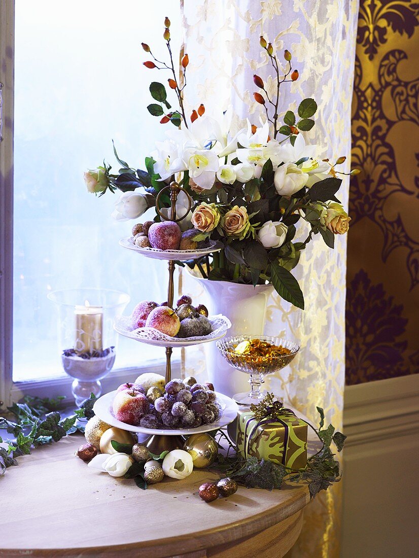 Etagere mit gezuckerten Früchten und Blumen am Fenster