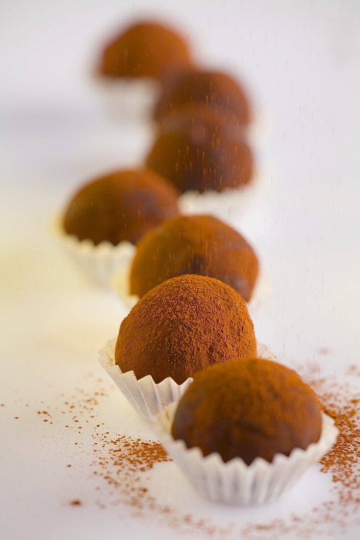 Sprinkling cocoa powder over chocolate truffles