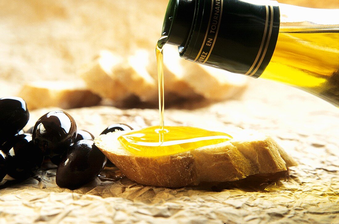Olivenöl auf ein Stück Brot gießen