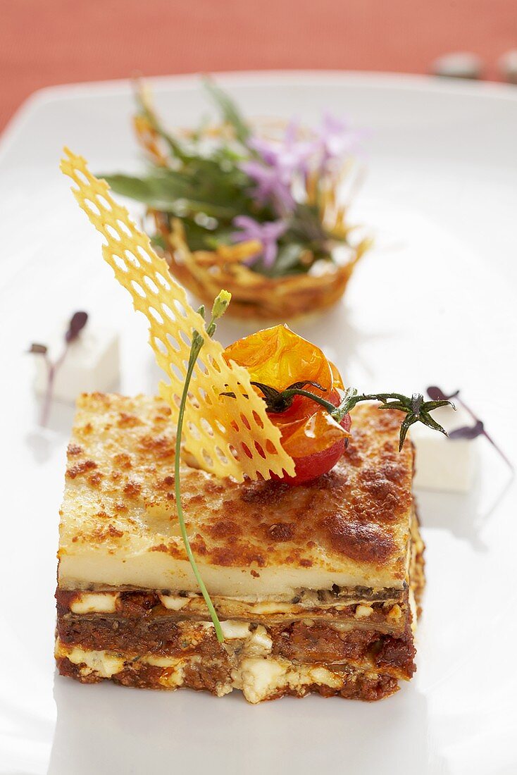 A portion of aubergine lasagne with baked tomato