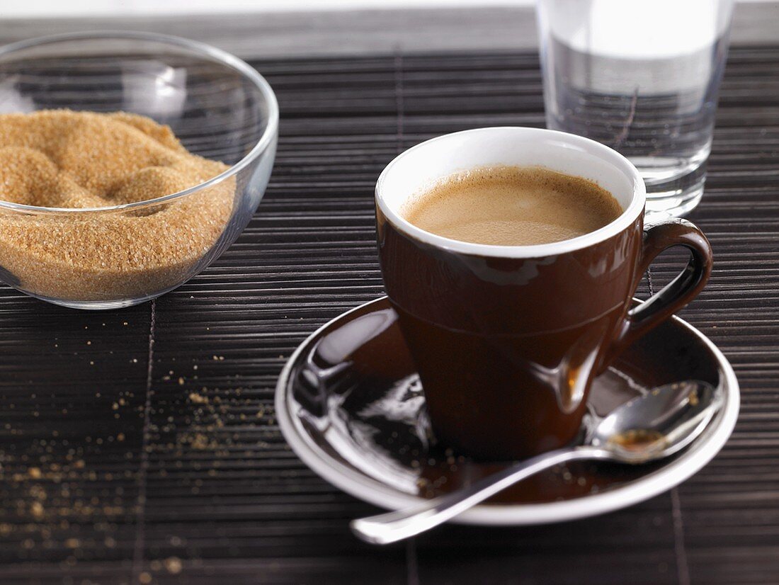 Eine Tasse Espresso mit Wasser und braunem Zucker