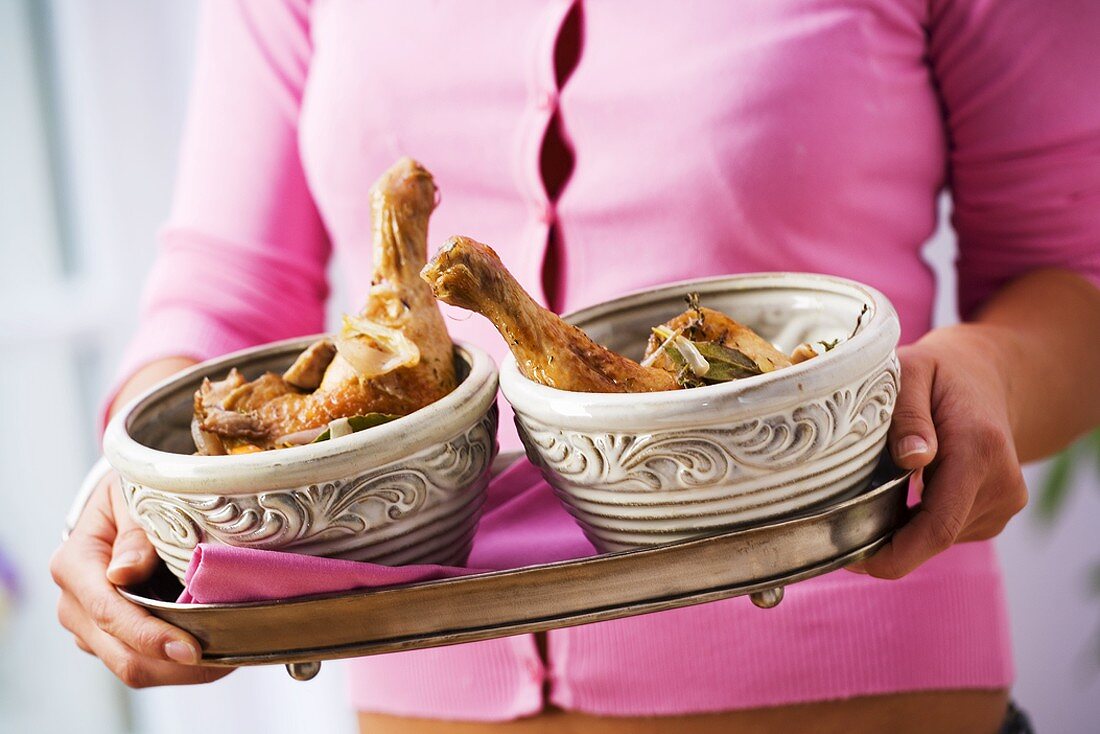 Woman carrying tray of coq au vin in two bowls