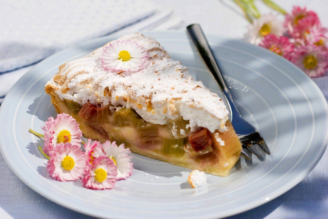 A piece of rhubarb meringue pie with bellis flowers