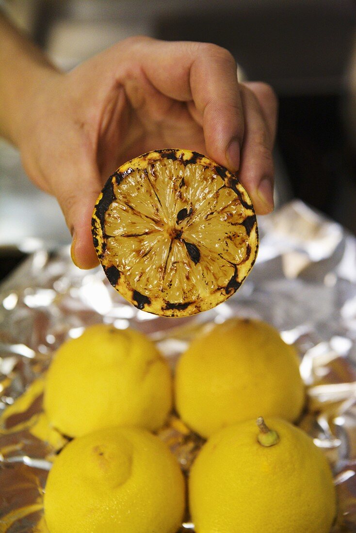 Hand hält eine geröstete Zitronenhälfte