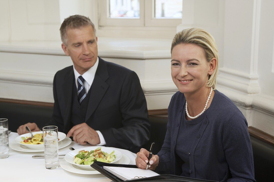 Geschäftsmann mit Sekretärin beim Essen im Restaurant