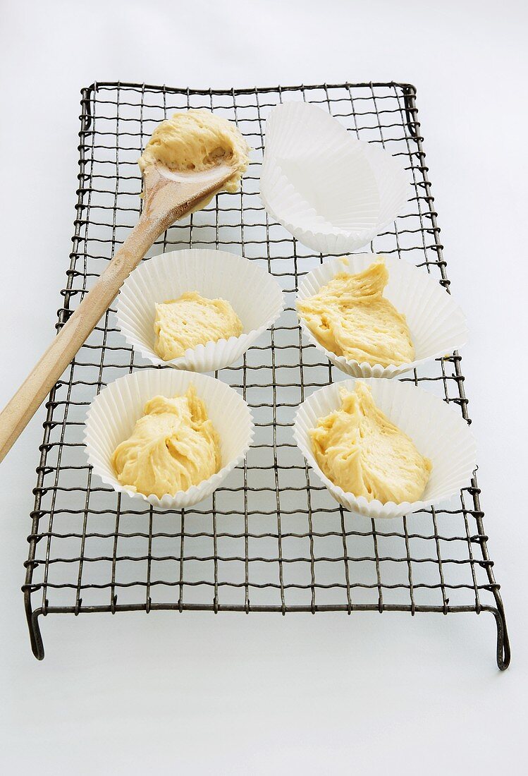 Paper cases filled with muffin dough on a wire rack