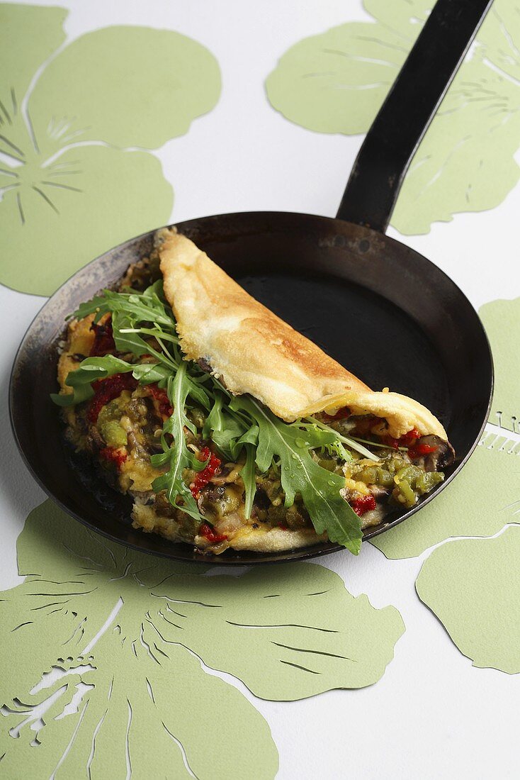 Omlette filled with mushrooms and rocket in a pan