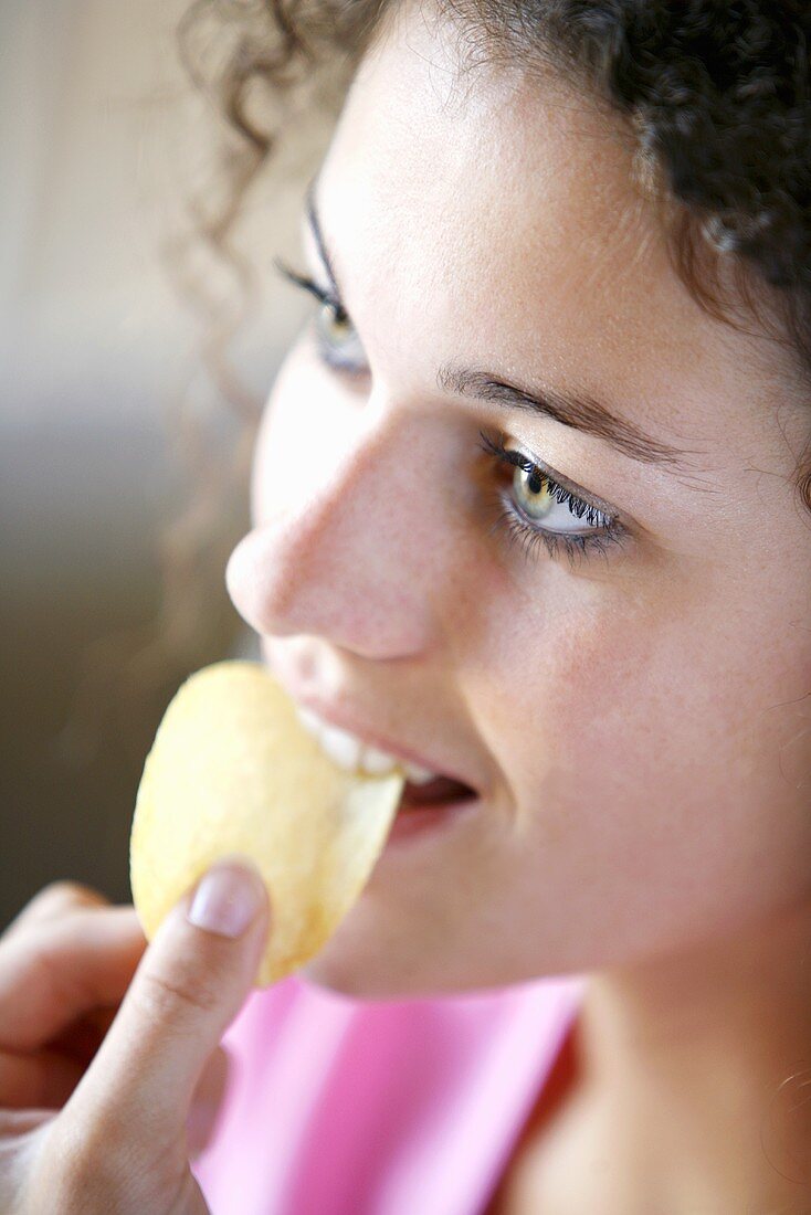 A young woman eating a crisp