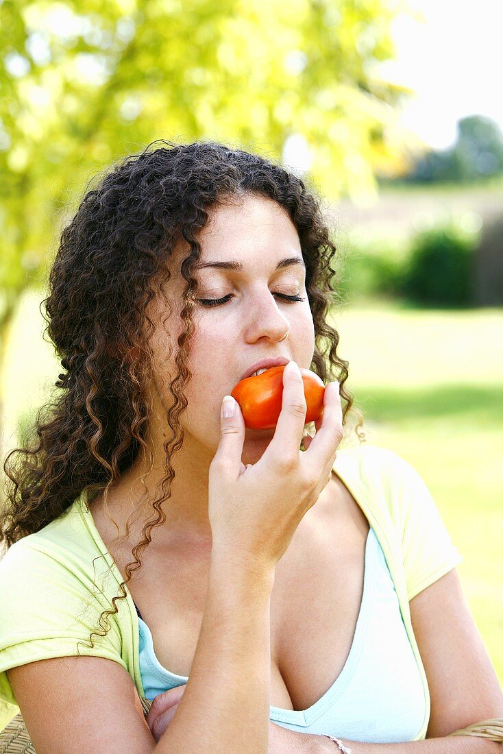 A young woman eating a tomato
