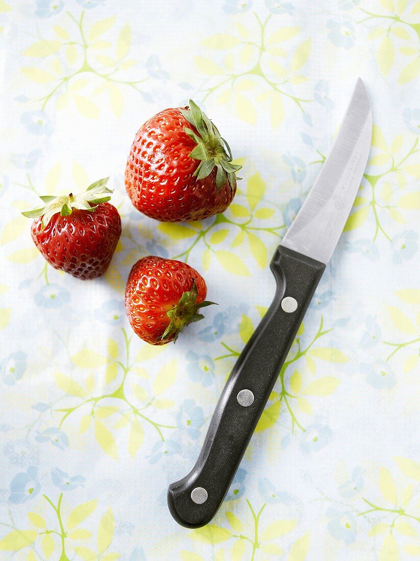 Three strawberries and a vegetable knife